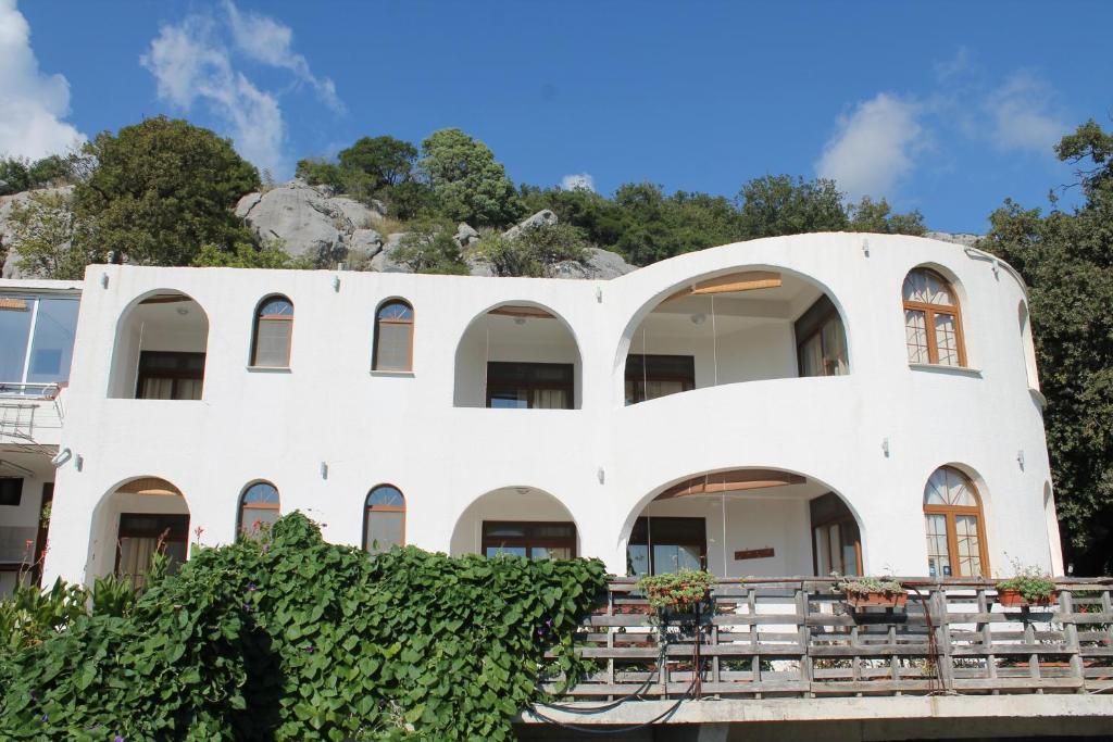 een wit gebouw met een berg op de achtergrond bij Pataki Guesthouse in Petrovac na Moru