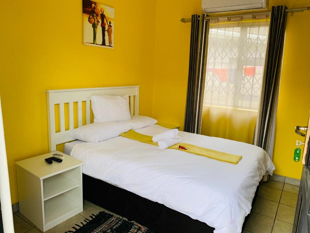 1 dormitorio con 2 camas, paredes amarillas y ventana en Sivande B&B, en Richards Bay