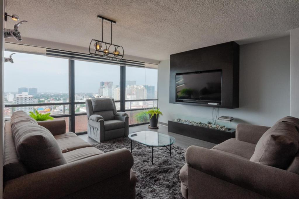 a living room with couches and a flat screen tv at Caravansaro Penthouse Polanco in Mexico City