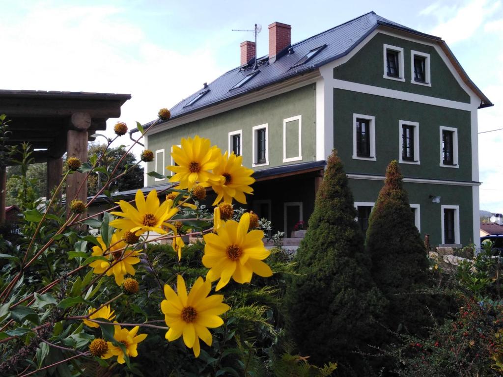 una casa con flores amarillas delante de ella en Apartmány Stará Škola, en Krásná Lípa