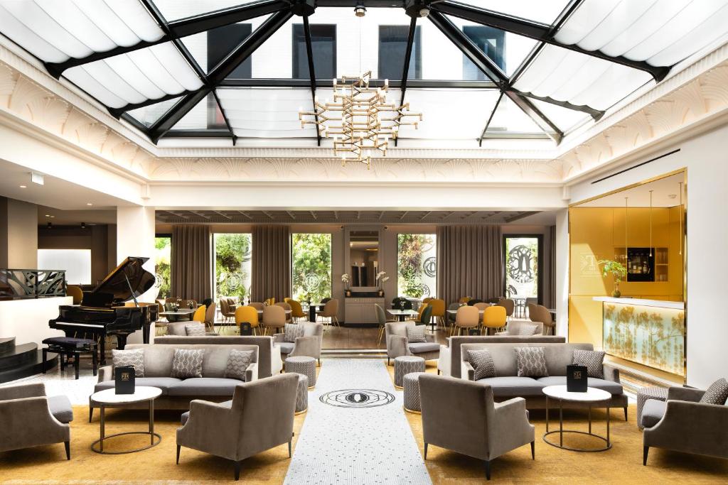 a large lobby with couches and a piano at Le Tsuba Hotel in Paris