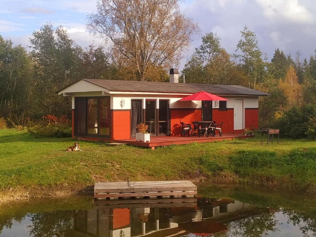 une petite maison rouge et blanche à côté d'un étang dans l'établissement Parila Holiday House with Sauna, à Parila