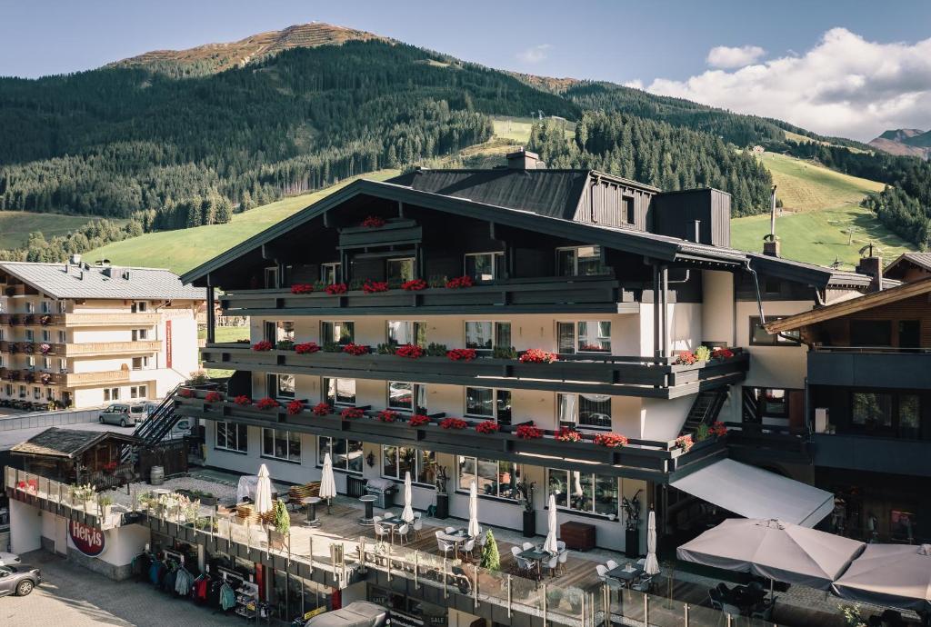 budynek z kwiatami na balkonach i góry w obiekcie Der Gollinger w Saalbach Hinterglemm