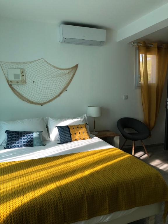 a bedroom with a bed with a yellow blanket and a chair at Maxima Sunset in Sainte-Maxime