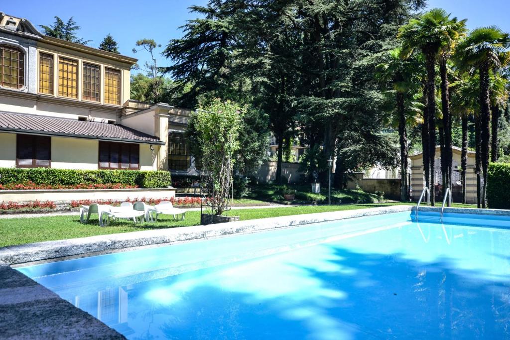 - une piscine en face d'une maison avec des palmiers dans l'établissement La Limonaia, à Tremezzo