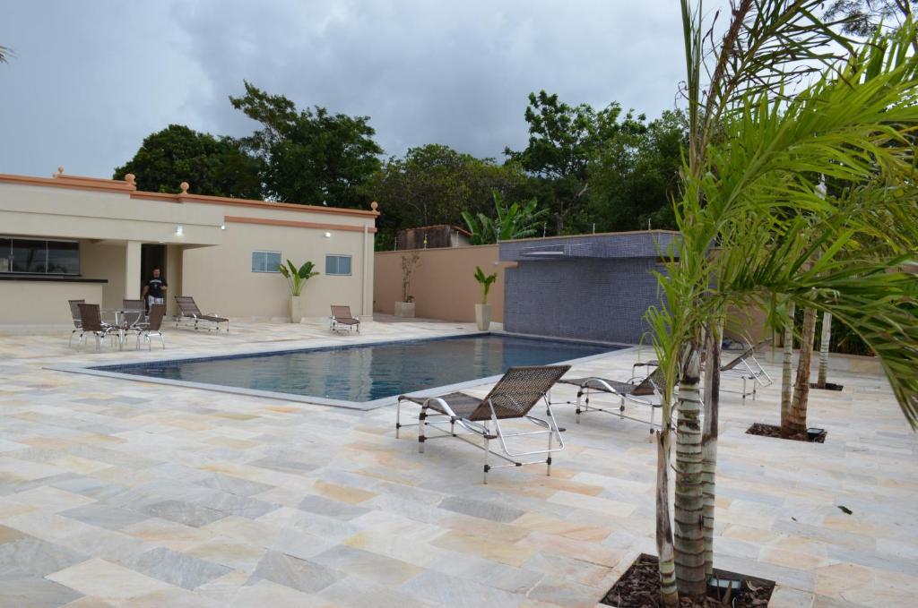 une piscine avec des chaises et un palmier dans une cour dans l'établissement Sakr Hotel Rio Preto, à Sao Jose do Rio Preto