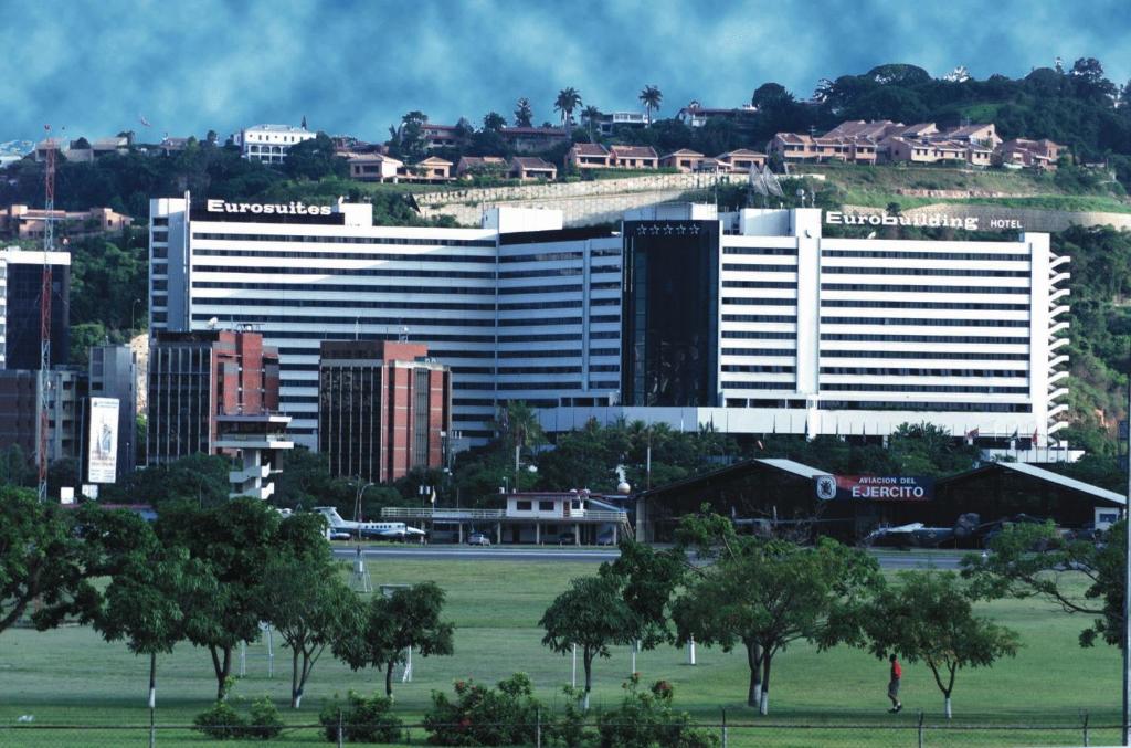 a large white building with trees in front of a city at Eurobuilding Hotel & Suites Caracas in Caracas