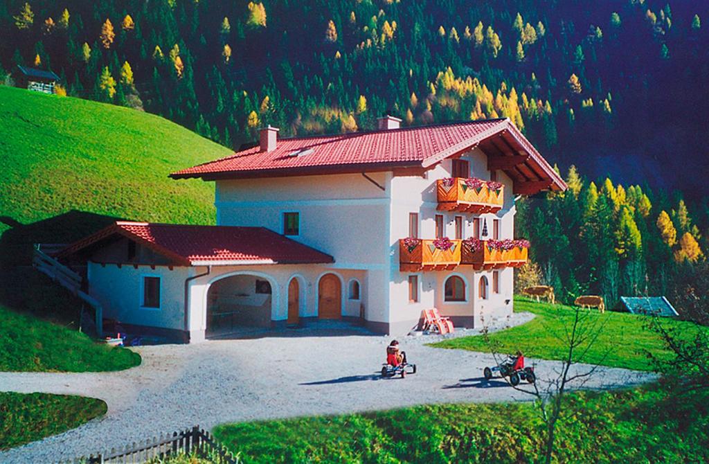 een klein huis met een rood dak op een heuvel bij Oberstockerhof in Sankt Johann im Pongau