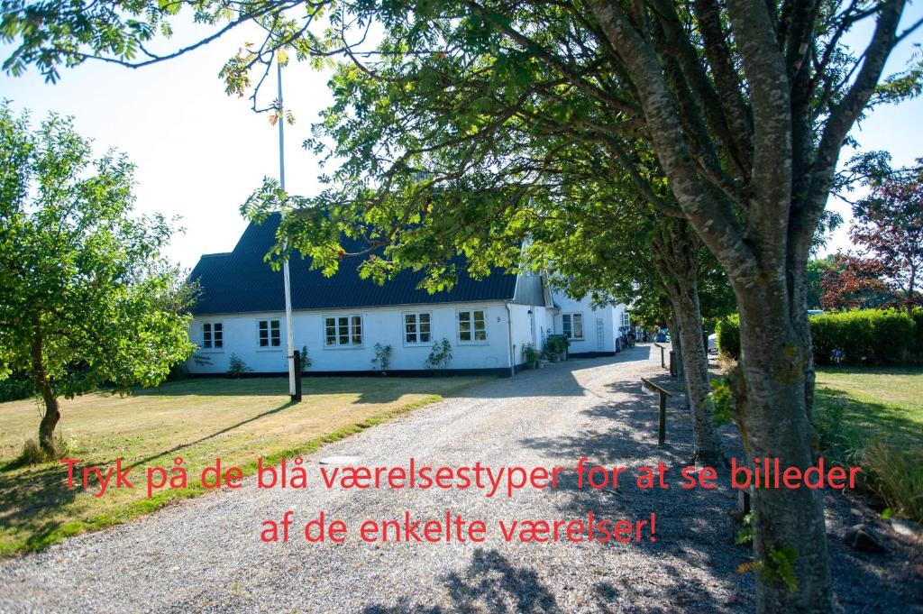 un edificio blanco con un árbol delante en Æblehaven, en Toftebjerg