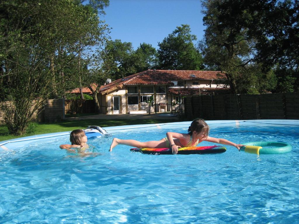 two young girls laying on inflatables in a swimming pool at Les Villas de Messanges in Messanges