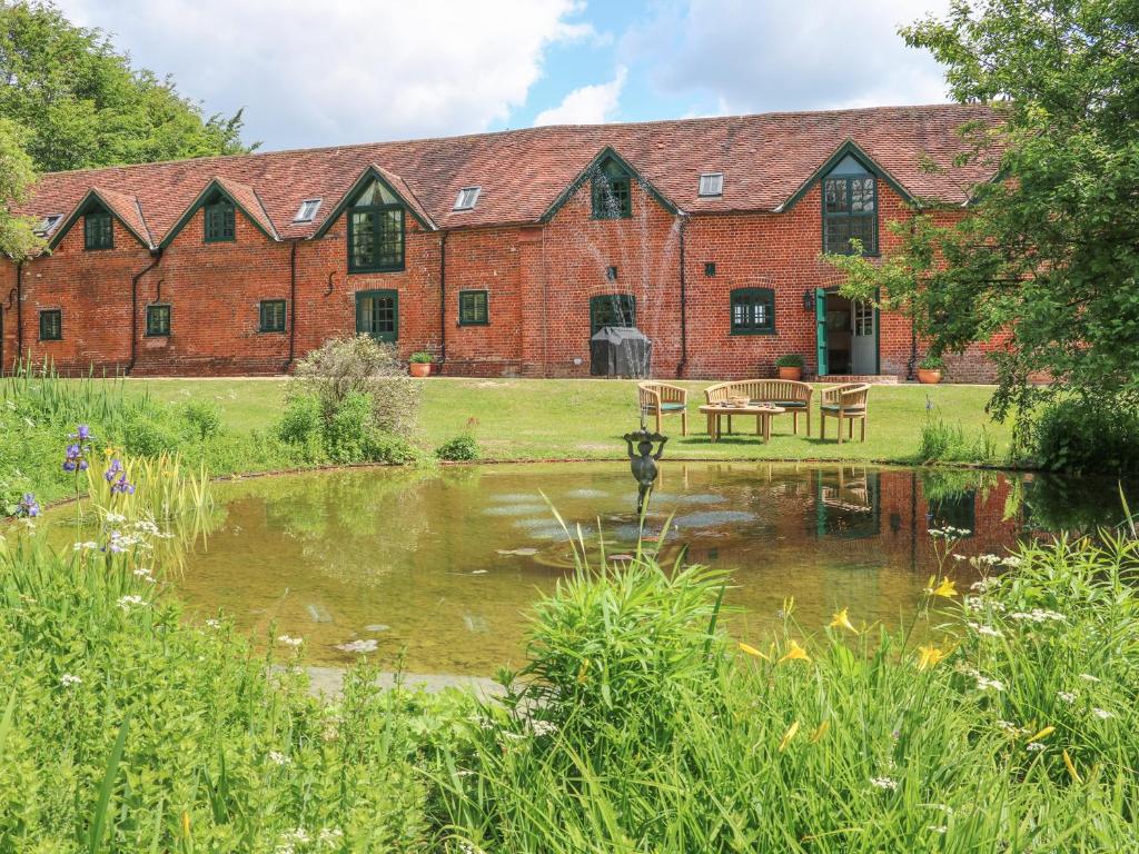a large brick building with a pond in front of it at Buckholt Stables in East Grimstead