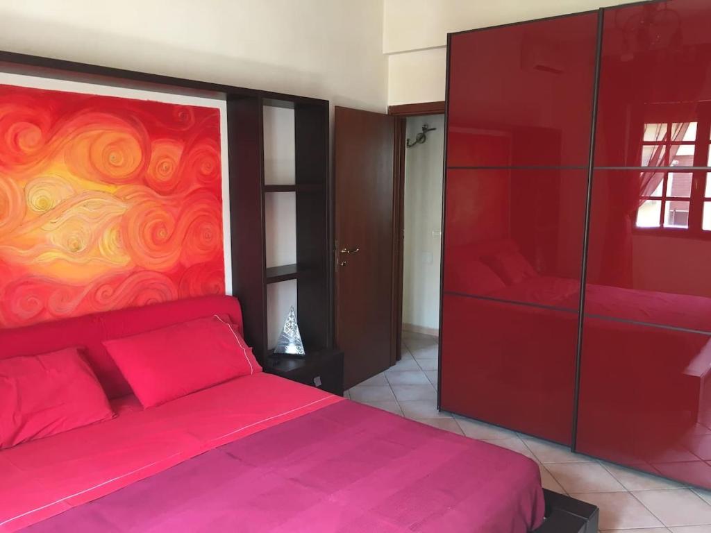 een slaapkamer met een rood bed en een schilderij aan de muur bij Casa Delfino - Appartamento Centro Storico a due passi dalla Spiaggia & Mare, Porto & Ferrovia in Civitavecchia