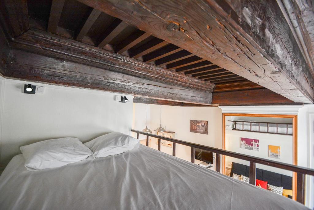 a bed in a room with a wooden ceiling at Le cocon des Deux Sirènes in Nancy