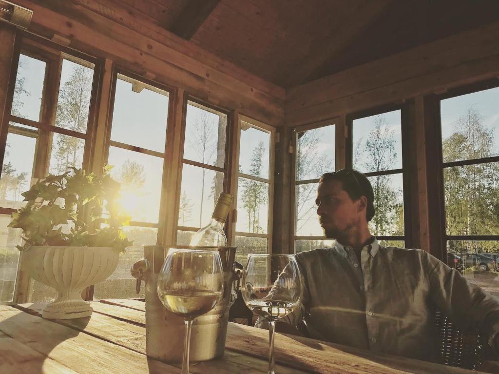 um homem sentado numa mesa com copos de vinho em Granlunda Gårdshotell em Gottby