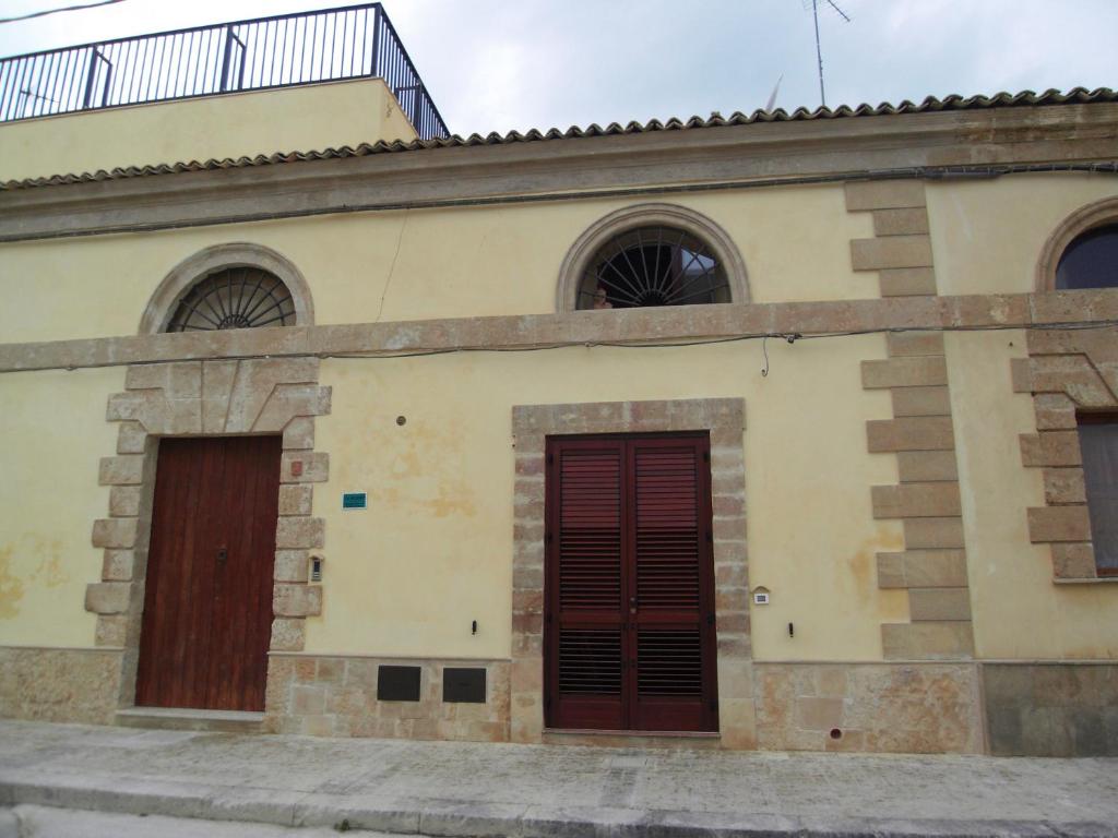 un edificio antiguo con puertas y ventanas rojas en Antica Casina di Pescatori, en Marina di Noto