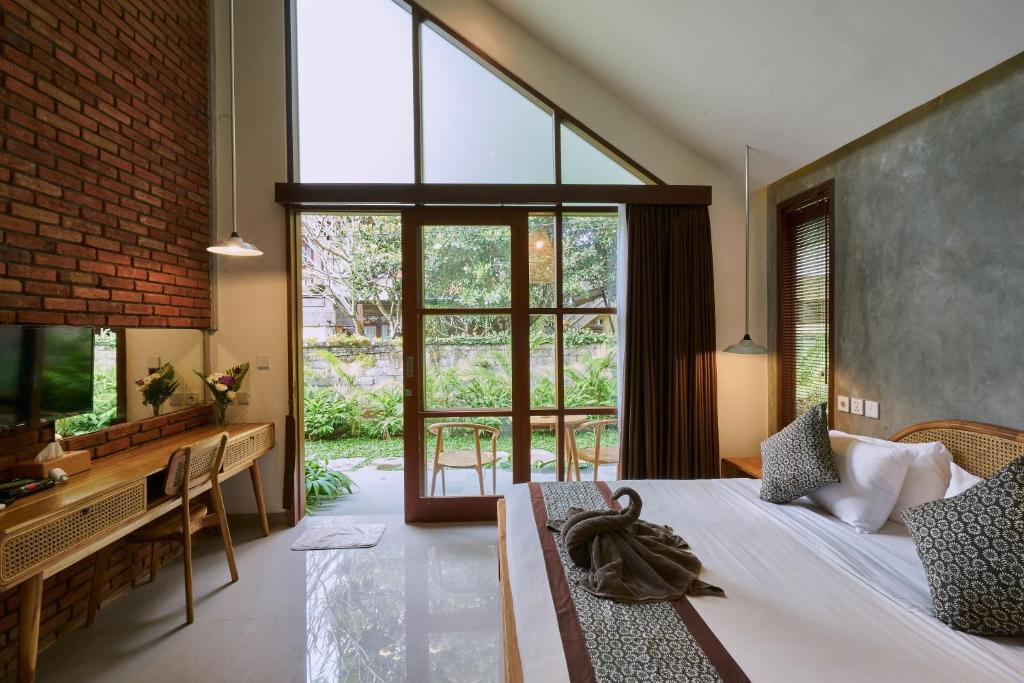 a bedroom with a bed and a large window at Yarama Cottages in Ubud