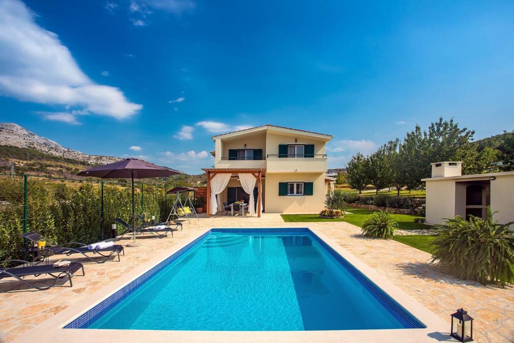 a villa with a swimming pool in front of a house at VILLA ROKO with 4 bedrooms, 32sqm heated pool in Tugare