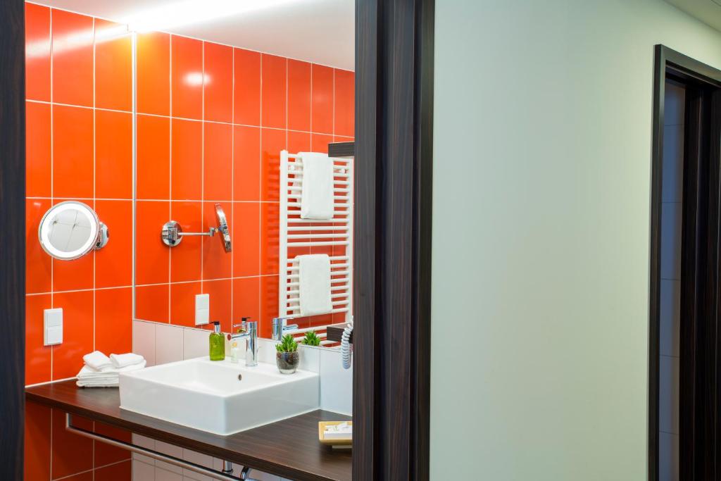 a bathroom with a sink and orange tiled wall at Heide Spa Hotel &amp; Resort in Bad Düben