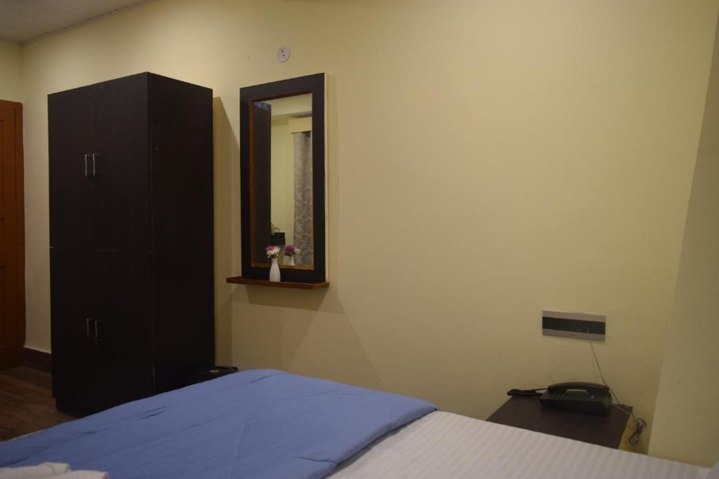 a bedroom with a bed and a dresser and a mirror at Denzong Khim in Gangtok