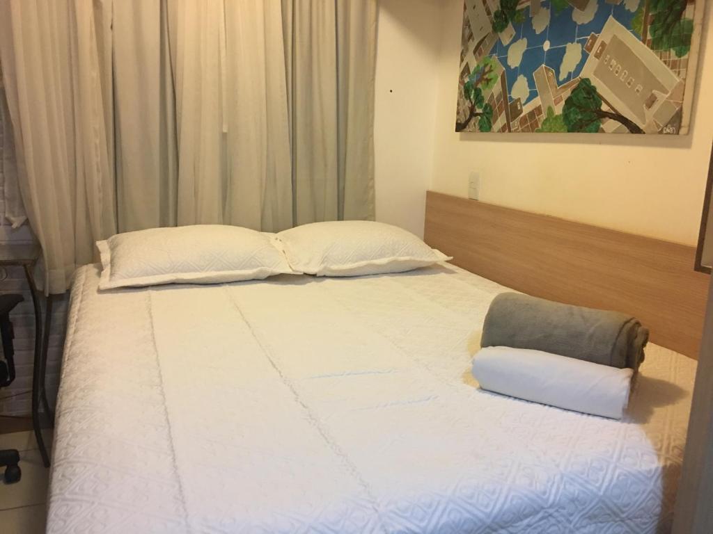 uma cama com lençóis brancos e almofadas num quarto em Life Resort - Flat Aconchegante em Brasília