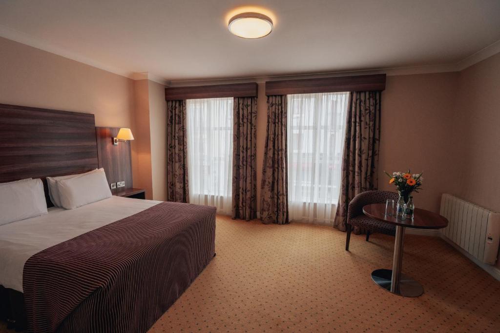 a hotel room with a bed and a table and windows at Dillon’s Hotel in Letterkenny