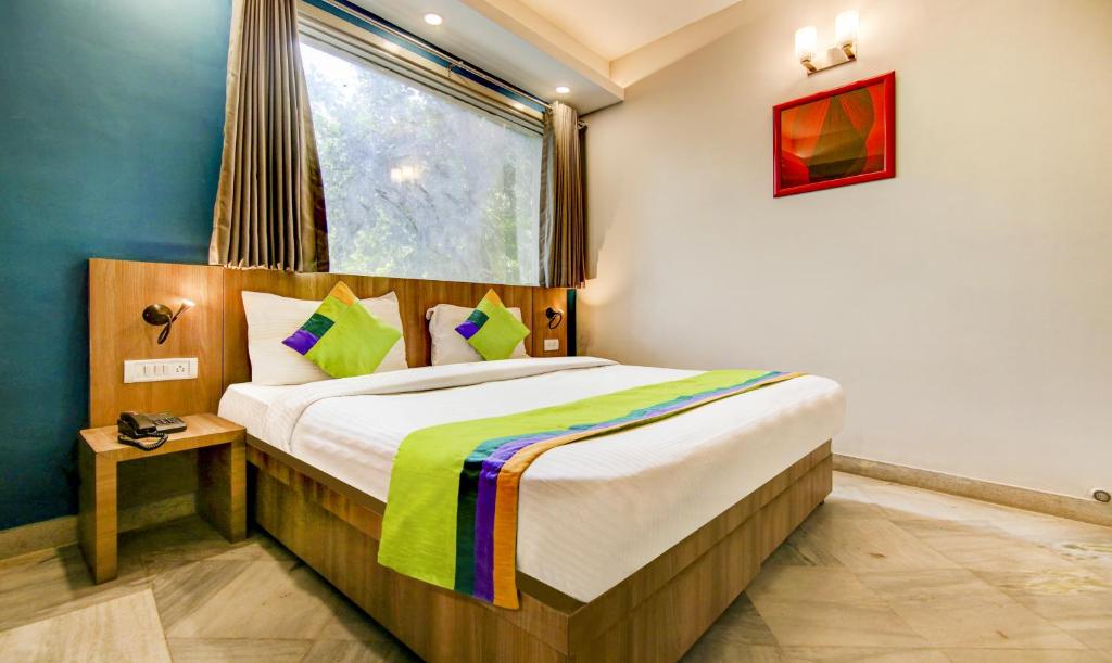 a bedroom with a large bed with a window at Treebo Trend Mall View DLF Phase II in Gurgaon