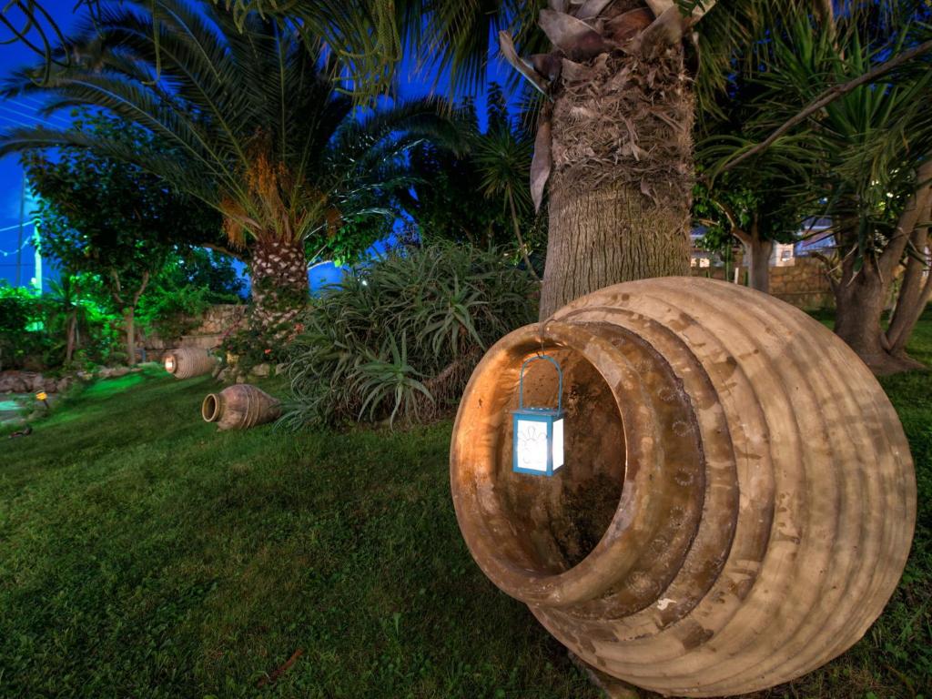 a wooden barrel sitting on the grass next to a tree at Calypso Studios in Amoudi