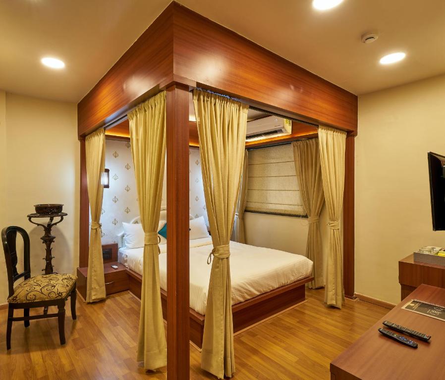 a bedroom with a canopy bed and a desk at Tranquil La Casa in Pune