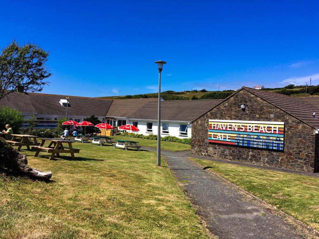 ein Gebäude mit Tischen und Bänken in einem Park in der Unterkunft YHA Broad Haven in Broad Haven