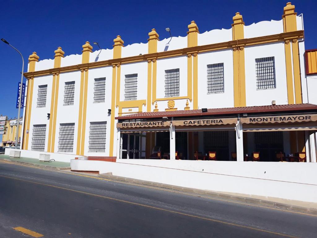 un edificio amarillo y blanco al lado de una calle en Hostal Montemayor, en Moguer