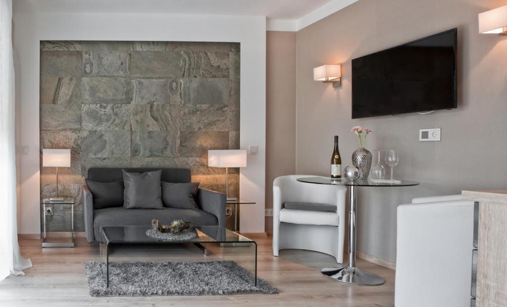 ein Wohnzimmer mit einem Sofa und einem TV in der Unterkunft Appart-Hotel REB_ART in Deidesheim