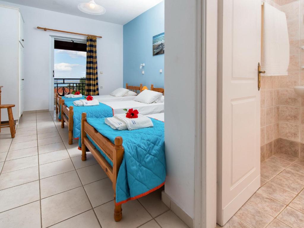 a row of four beds in a room with a balcony at Calypso Studios in Amoudi