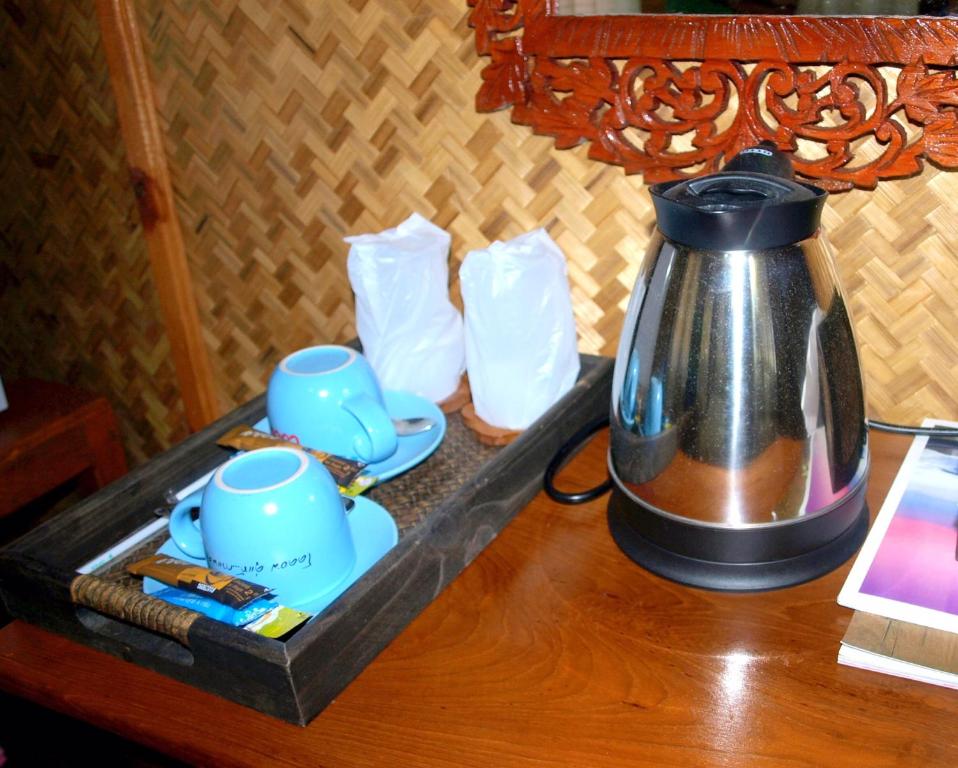 a tea kettle and cups on a wooden table at Suandarbporn Resort Mae Sot in Mae Sot