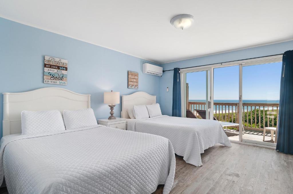 two beds in a bedroom with a view of the ocean at Wavecrest Resort in Montauk