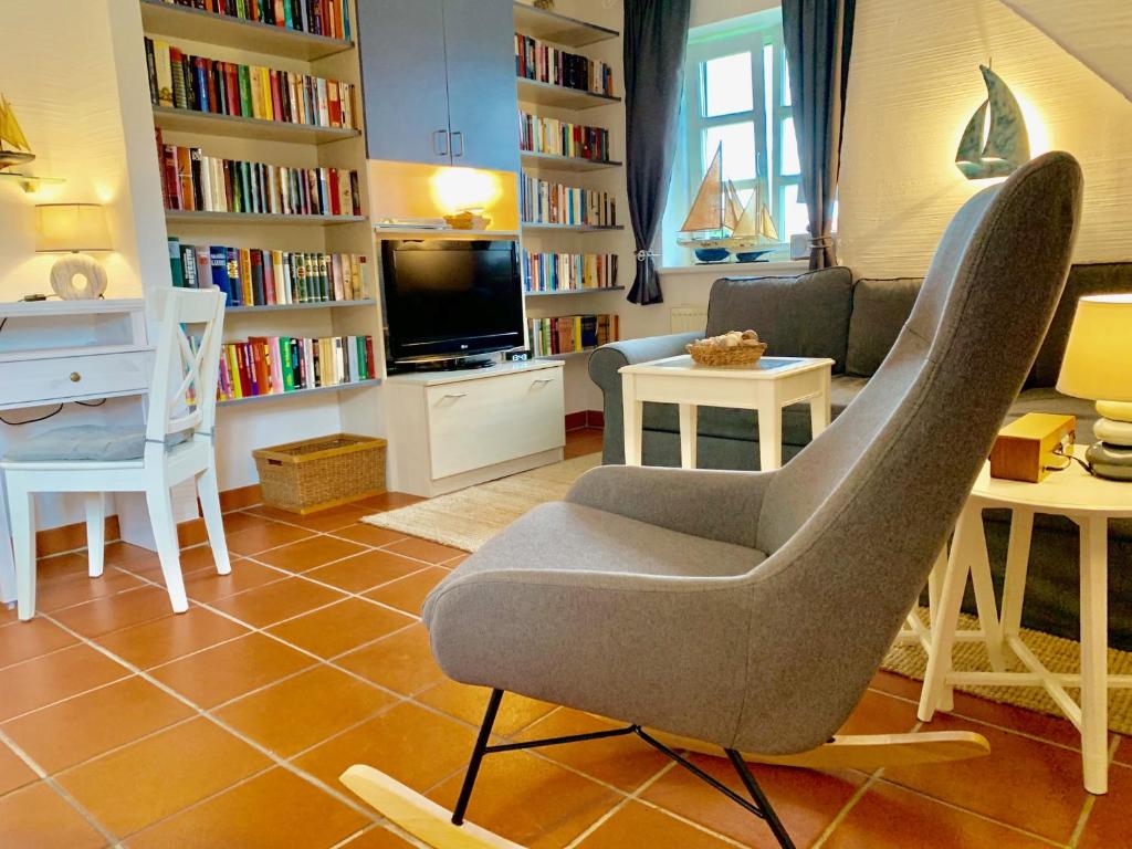 a living room with a chair and a tv and bookshelves at Strandnahe Ferienwohnung Rügen in Dranske