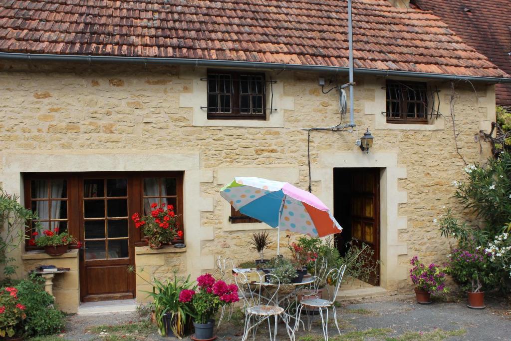 une table avec un parasol devant un bâtiment dans l'établissement chez Jeannette, à Marcillac-Saint-Quentin