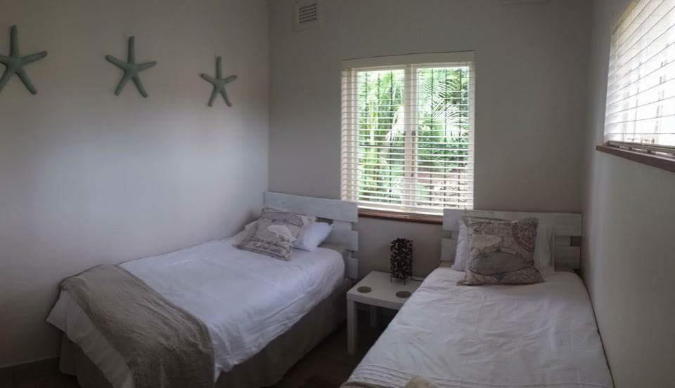 a bedroom with two beds and a window at Salt Life in Port Shepstone