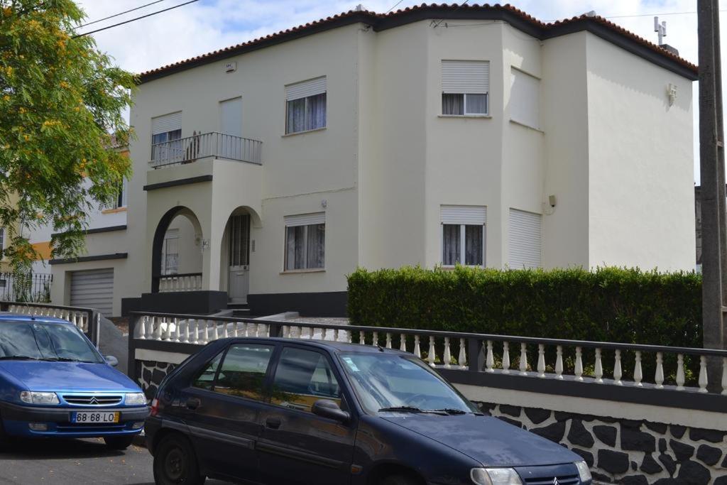 dois carros estacionados em frente a um edifício branco em Casa Brito Aguiar em Angra do Heroísmo