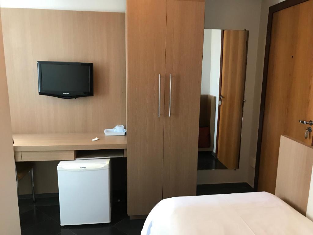 Cette chambre comprend un lit et un bureau avec une télévision. dans l'établissement Sete Lagoas Residence Hotel, à Sete Lagoas