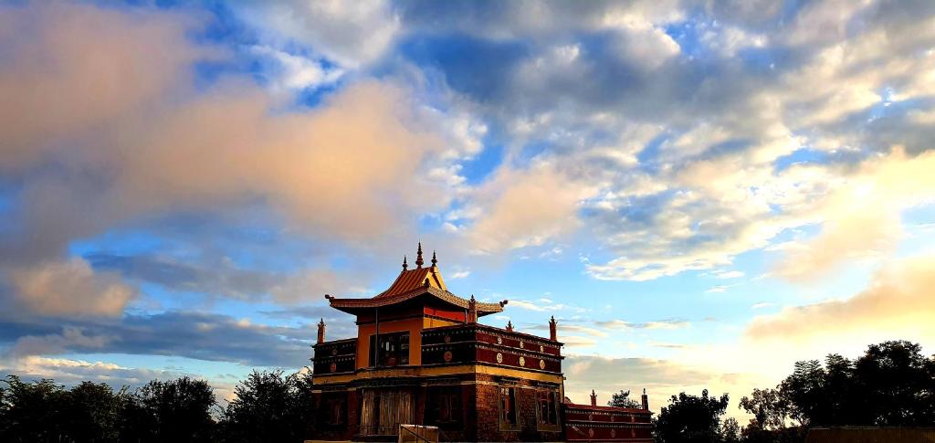 ein Gebäude mit wolkigem Himmel im Hintergrund in der Unterkunft Buddha House Himalayan Brothers in Dharamshala