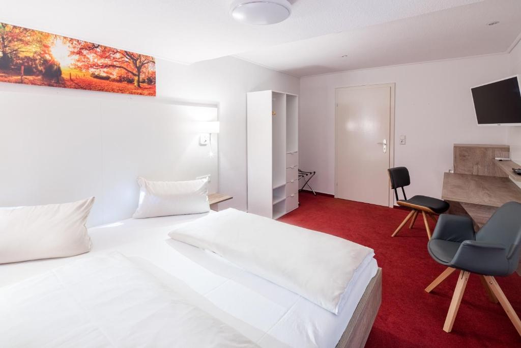 um quarto com uma cama branca, uma secretária e uma cadeira em Hotel Hopener Wald ,Self Check In em Lohne