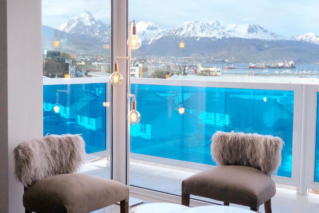 a room with two chairs and a large window with mountains at Bien al Sur in Ushuaia