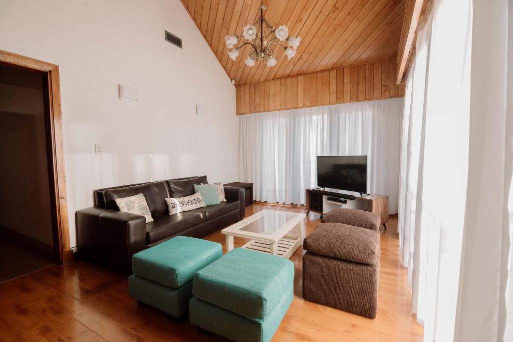 sala de estar con sofá, sillas y TV en Casa Jainen en Ushuaia