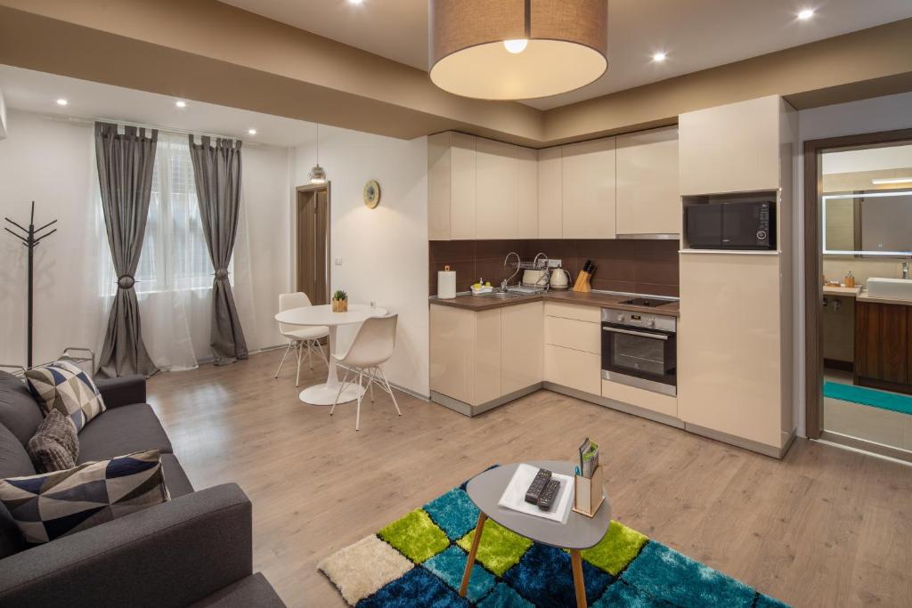 a living room and kitchen with a couch and a table at Kastely Apartments - Buda Castle in Budapest