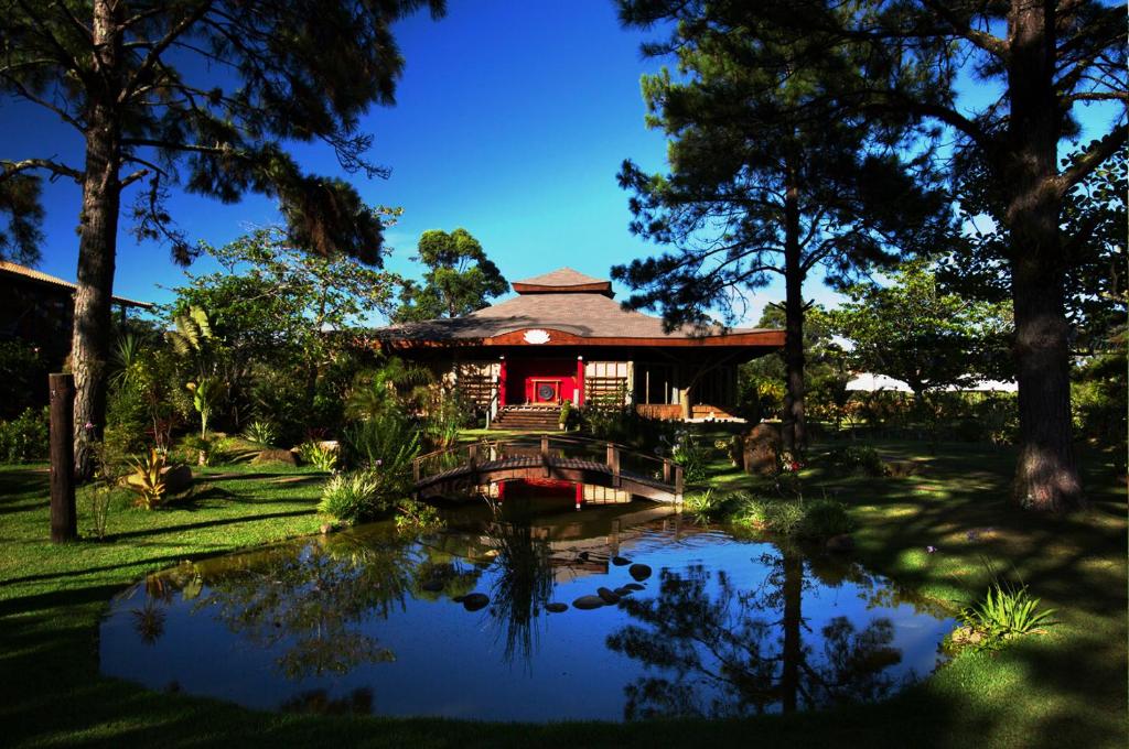 uma casa com um lago em frente em Pousada Mevlana Garden em Barra de Ibiraquera