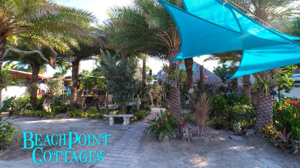 a blue umbrella in a garden with palm trees at BeachPoint Cottages in Siesta Key