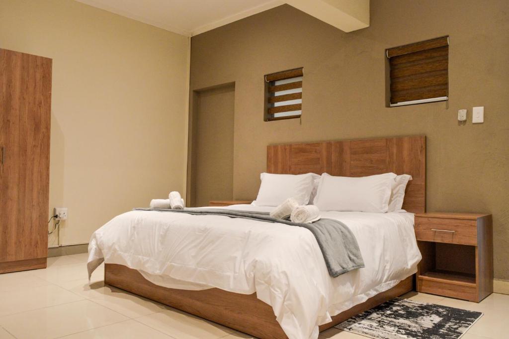 um quarto com uma cama grande e lençóis brancos em Millennium hotel em Joanesburgo