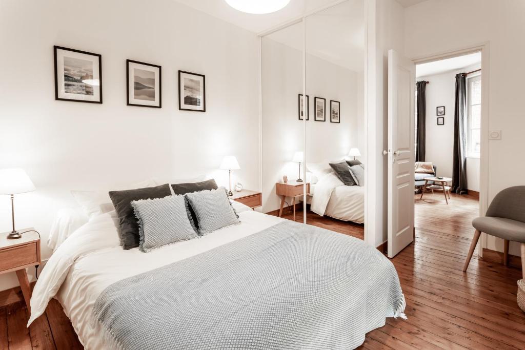 1 dormitorio blanco con 1 cama grande y 1 silla en Au Coeur De La Ville, en Honfleur