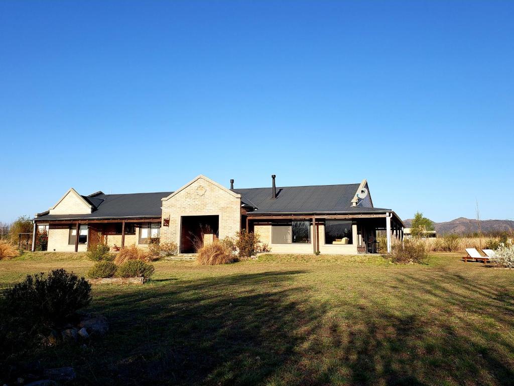 a house with a black roof on a grass field at Refugio Del Guira Guira in Los Reartes