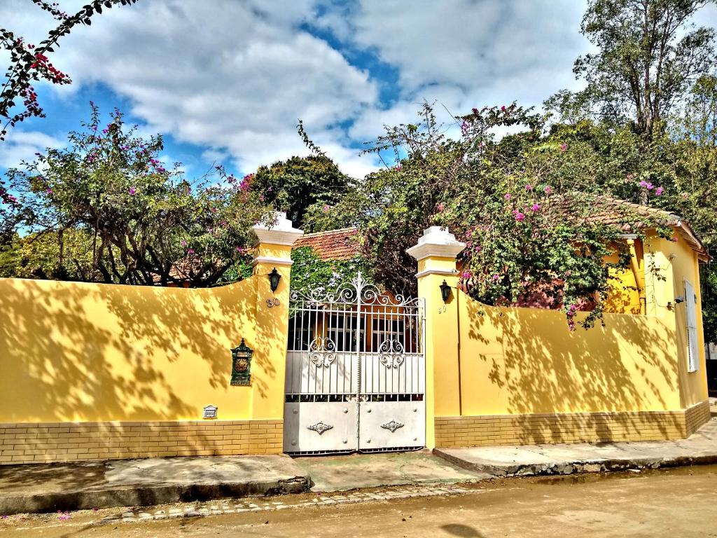 a yellow fence with a gate in front of a house at Casa de Noca Paquetá in Rio de Janeiro